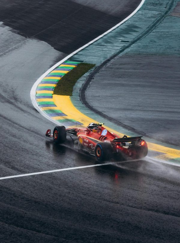 Ferrari Formula 1 car navigating a wet curve at Interlagos race track in Brazil.