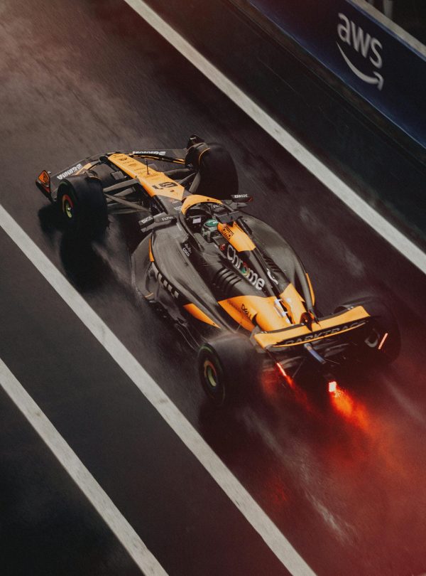 Formula 1 car speeding on a wet track during a race, showcasing dynamic motion and sportsmanship.